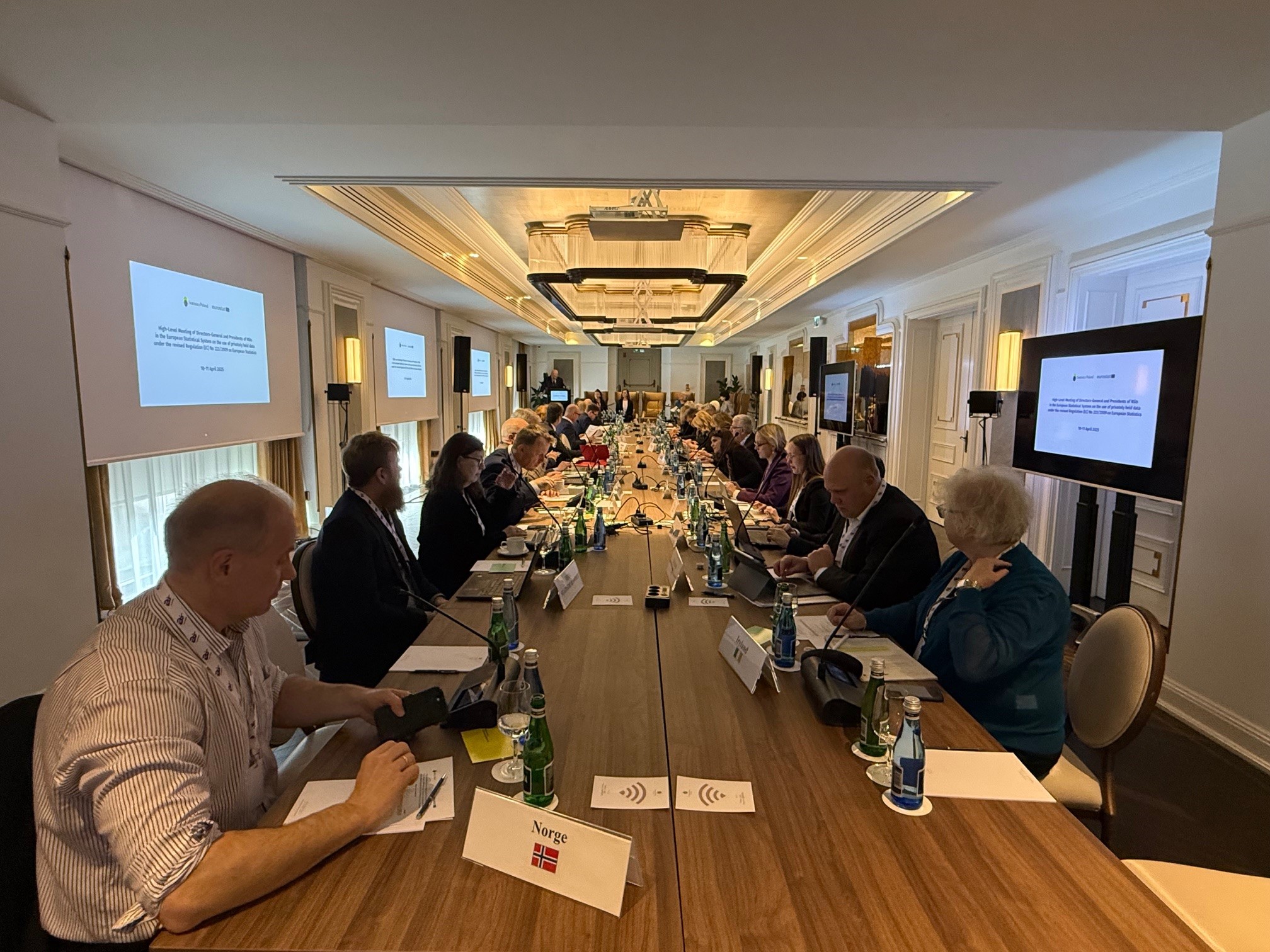 Zoom in  - Panoramic view of the participants seated at the long conference table