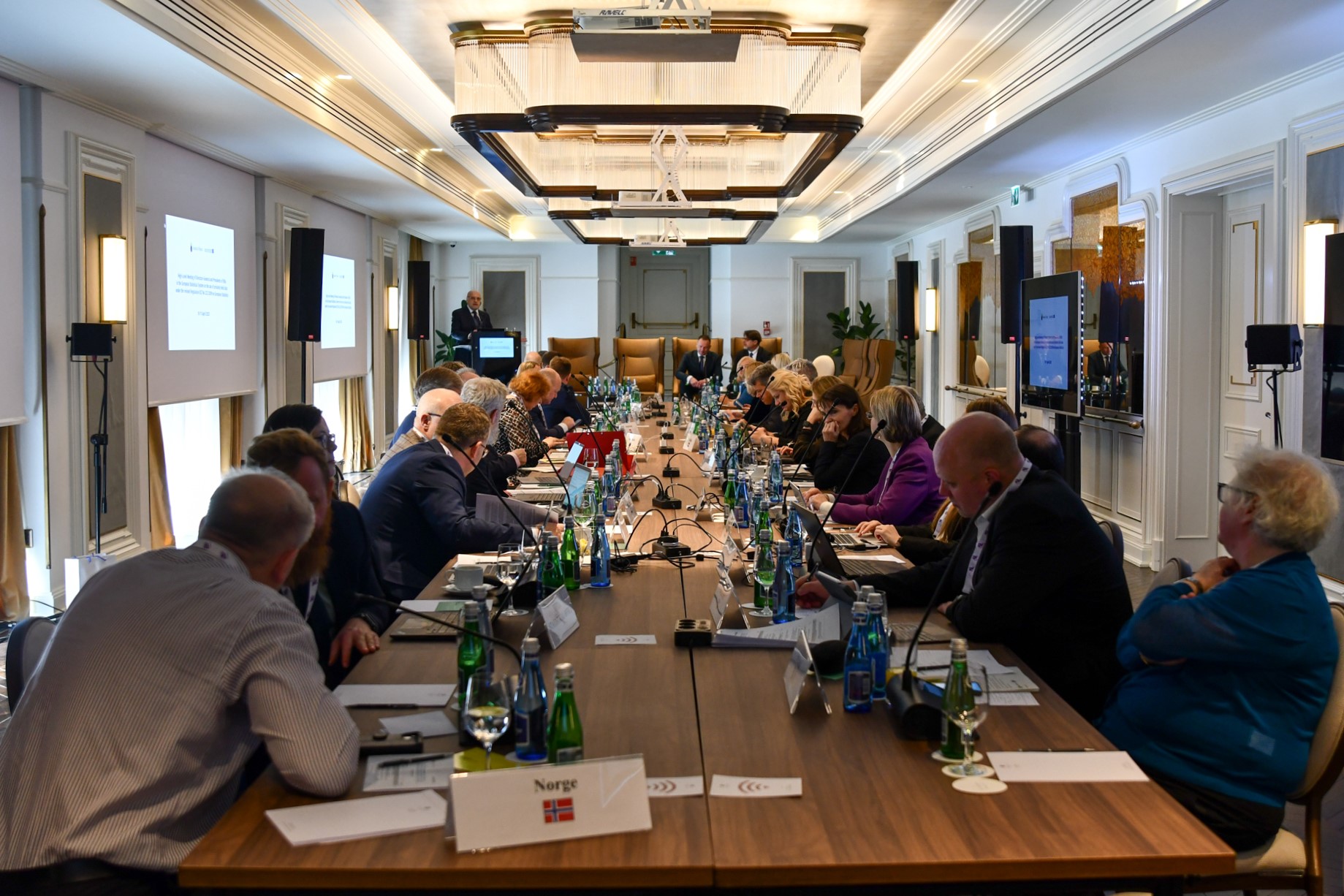Zoom in  - Panoramic view of the participants seated at the conference table, during the speech of Marek Cierpiał-Wolan from Poland